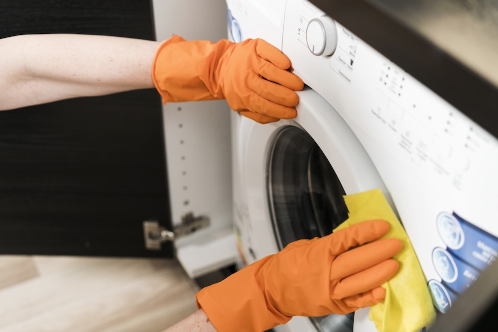 žena v oranžových gumových rukavicích čistí pračka